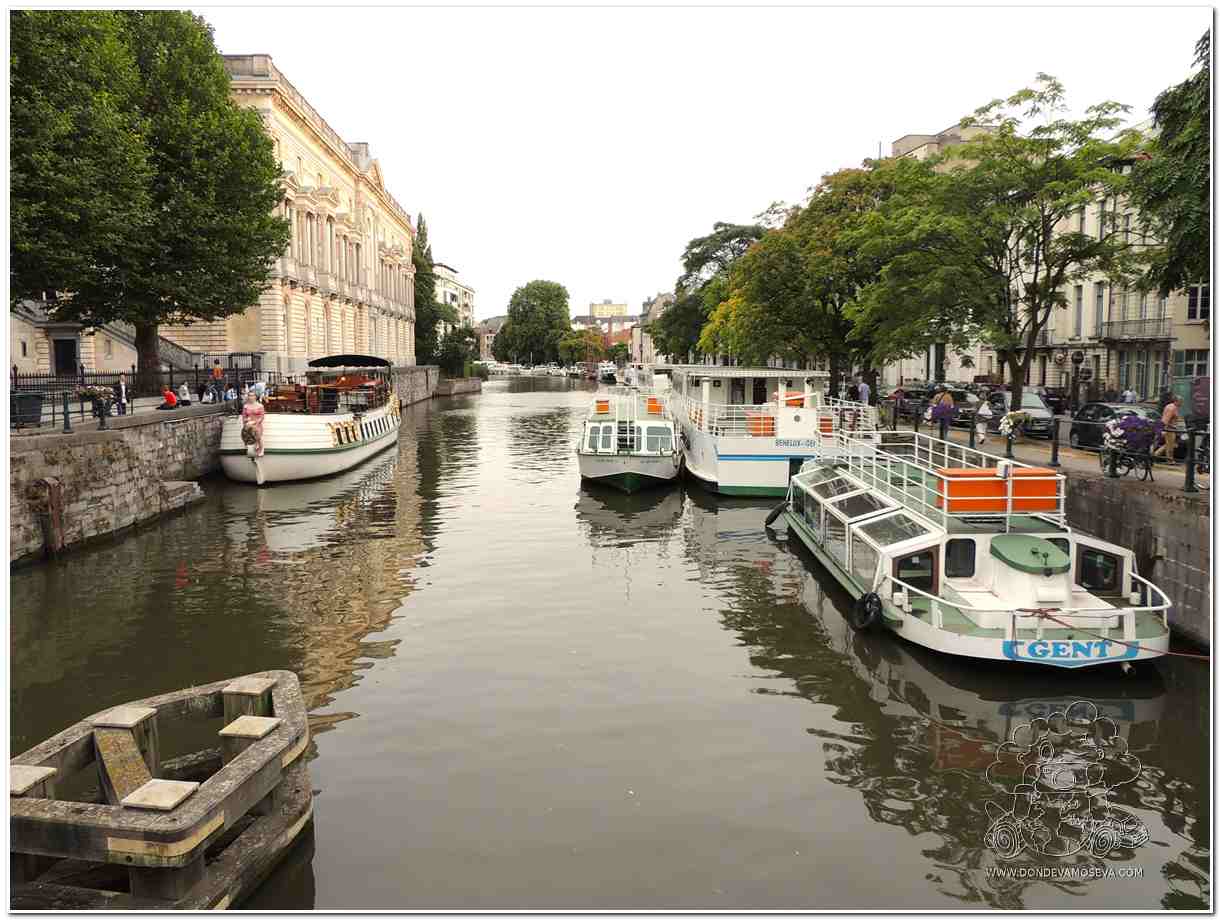"Canales de Gante iluminados al atardecer con reflejos en el agua"