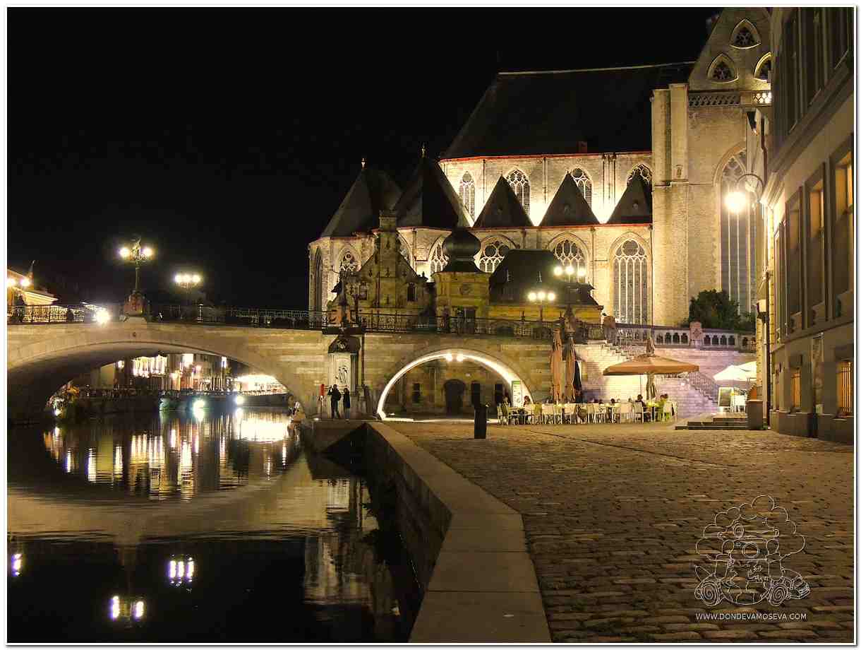 Iglesia de San Miguel iluminada de noche vista desde el muelle de Gante