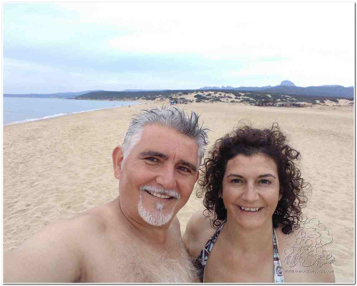 Pareja de viajeros en la playa Piscinas, sonrientes tras llegar a uno de los lugares más salvajes de la Costa Verde en Cerdeña