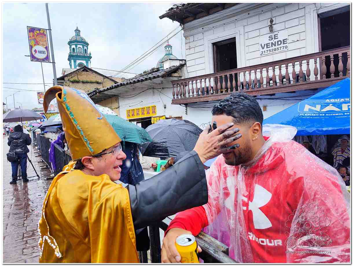 Persona aplicando la pintica en el rostro de otra durante el Carnaval de Negros y Blancos de Pasto, símbolo de igualdad y respeto.