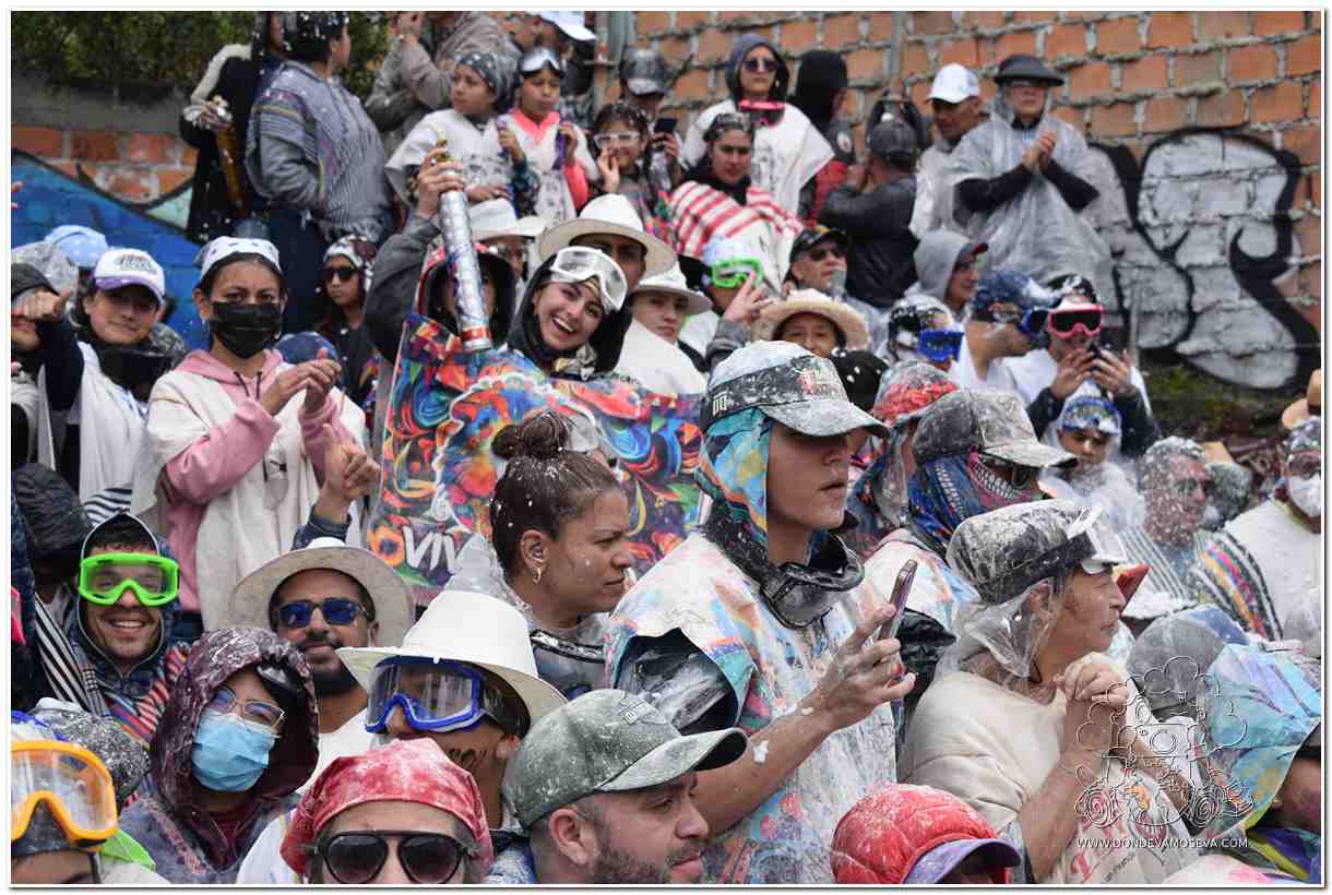 Público del Carnaval de Negros y Blancos con gafas, ponchos y gorros de colores participando del juego