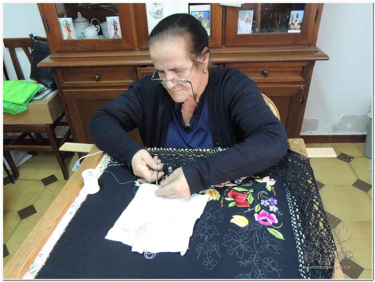 Costurera anciana elaborando chal tradicional en Oliena
