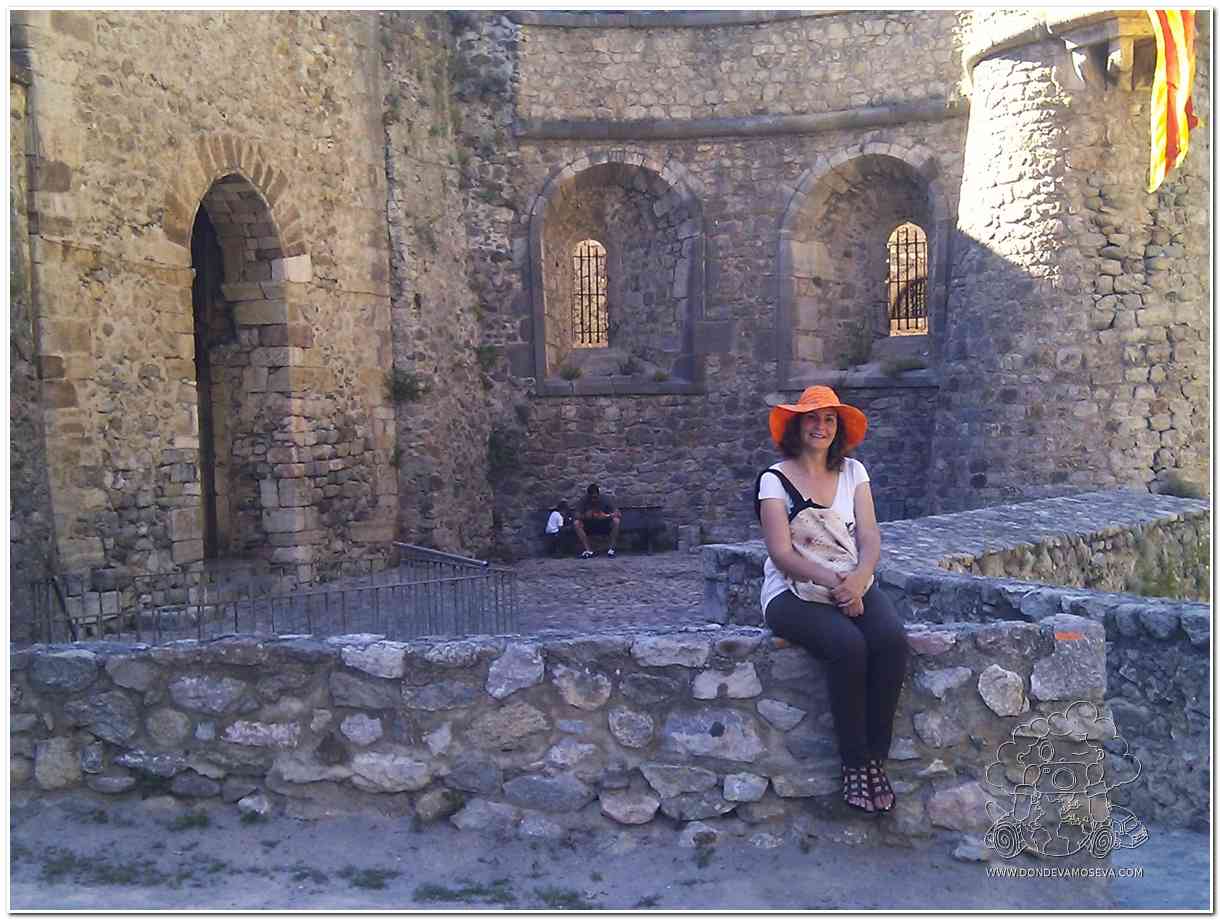 Mujer sentada frente a las murallas medievales de Villefranche-de-Conflent, uno delos pueblos más bonitos de Pirineos Orientales