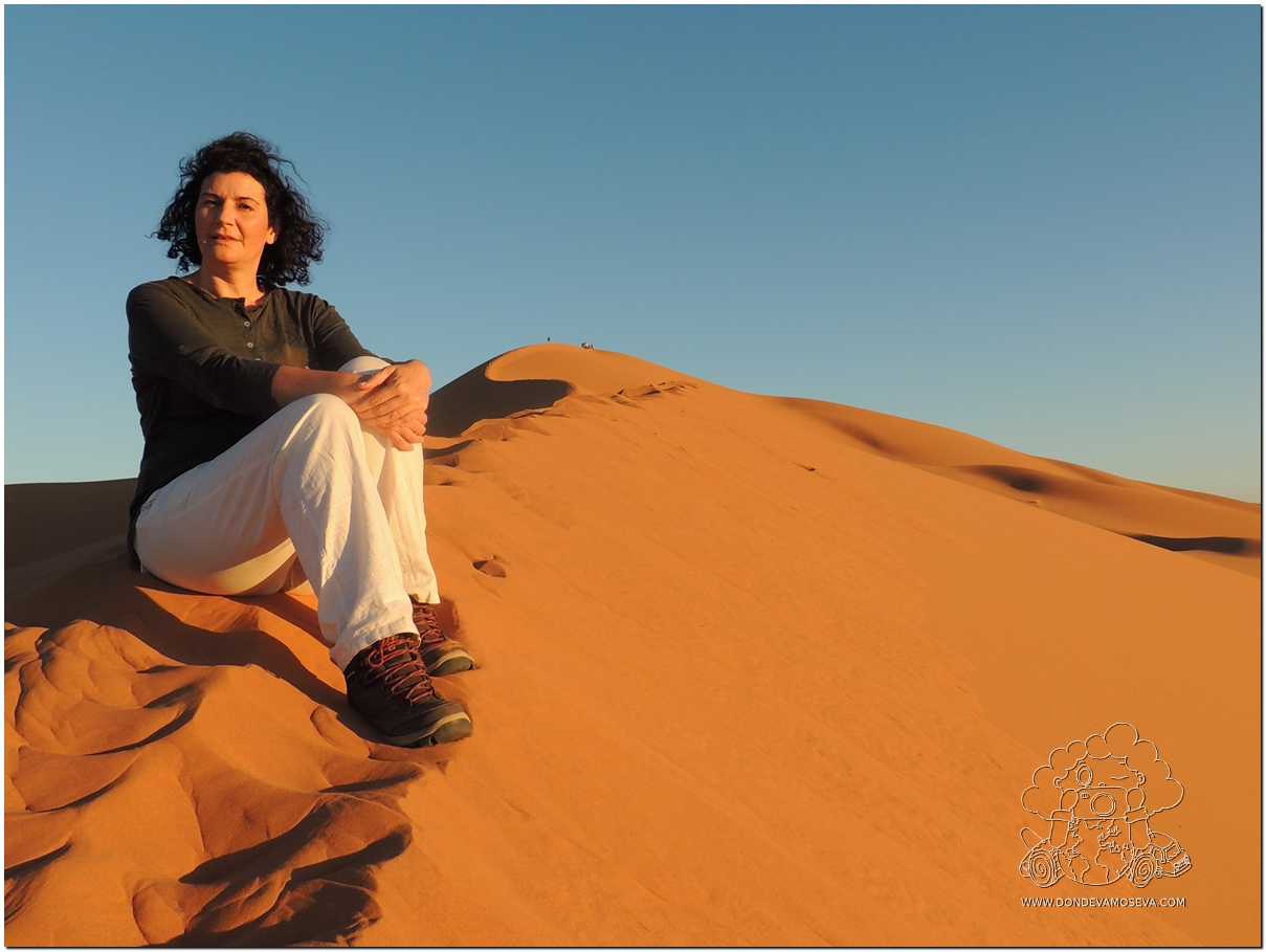 Mujer reflexionando sobre una gran duna del desierto de Erg Chebbi en Marruecos