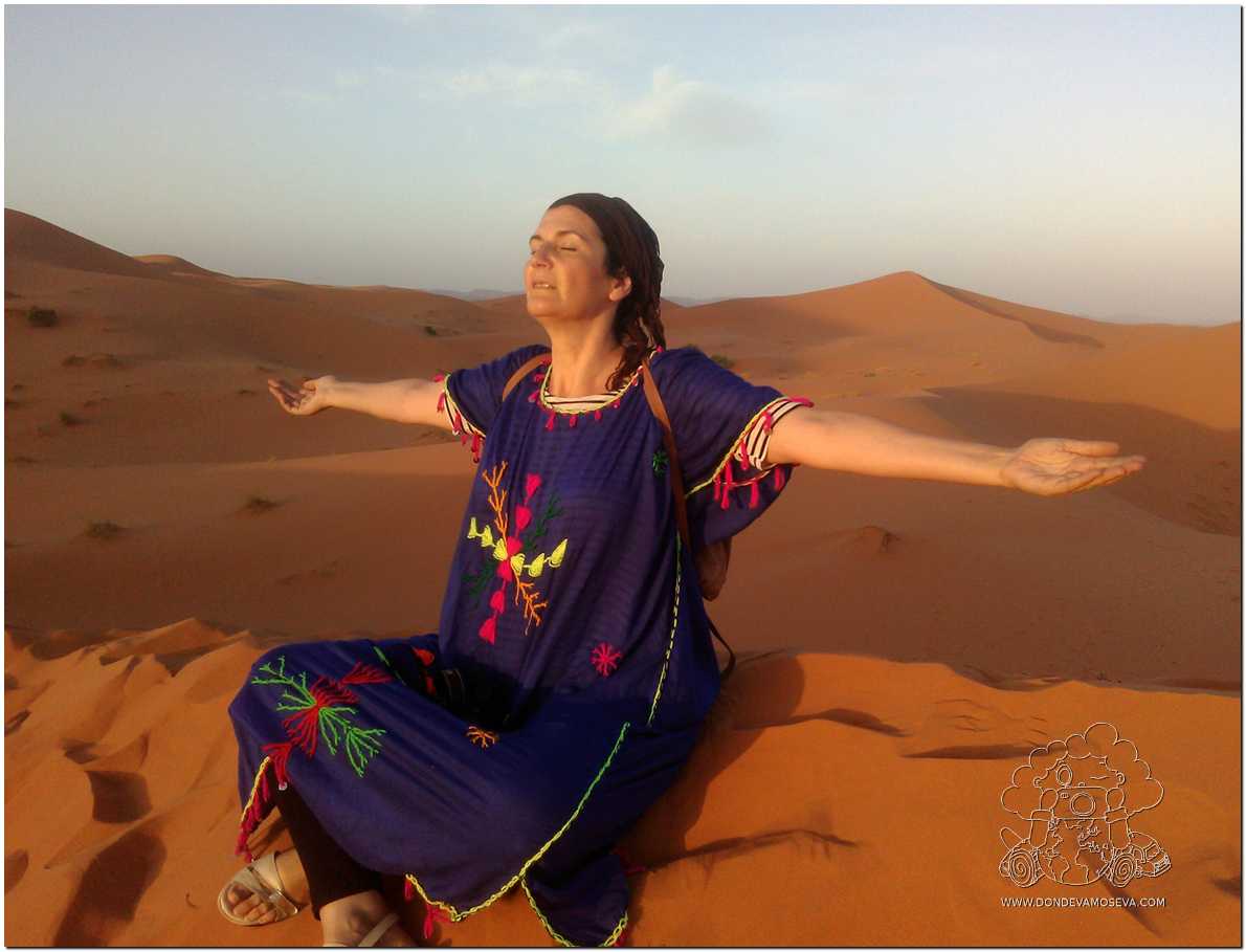 Mujer sentada tranquilamente sobre una duna en el desierto de Merzouga Marruecos